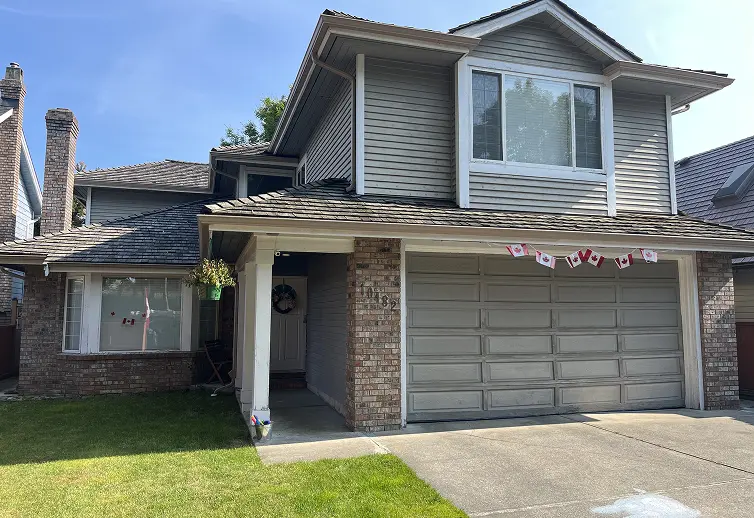 Dated beige residential house siding and dark garage door before a modern color transformation