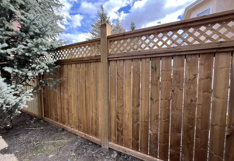 Weathered and unpainted wood privacy fence in Calgary before a professional painting and staining service.