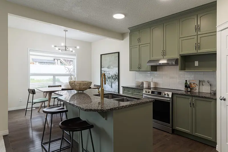 Professional kitchen cabinet painting by Color Works Painting showcasing trendy sage green upper and lower cabinets with matching kitchen island.