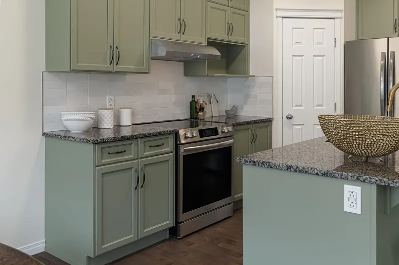 Close-up of smooth, factory-finish kitchen cabinet painting in a modern sage green color executed by Color Works Painting.