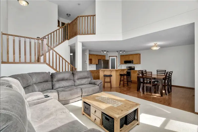 High-ceiling living room interior painting by Color Works Painting, showcasing expert cutting-in around a grand wooden staircase.