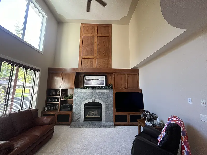 Freshly painted Calgary living room with vaulted ceilings, custom wood fireplace surround, and warm neutral wall colors.