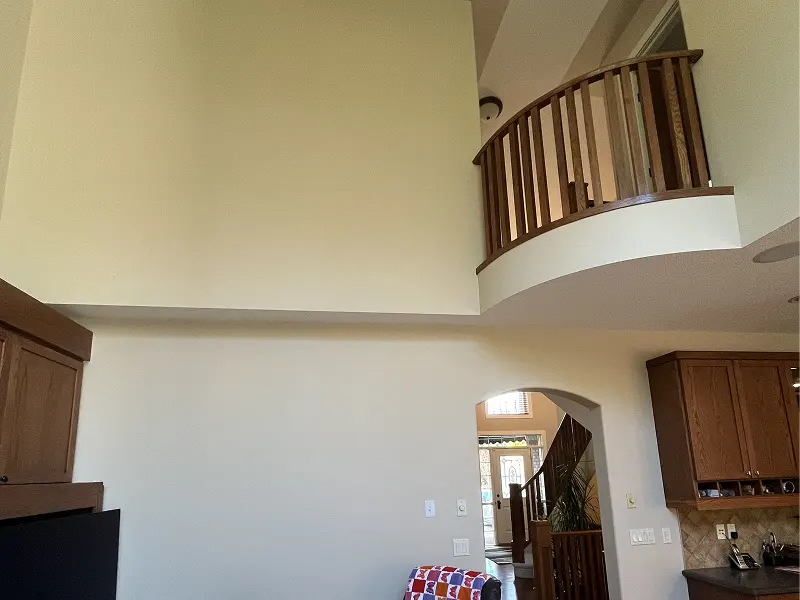 Newly painted high-ceiling interior wall in a Calgary home with clean beige tones and open-concept design.