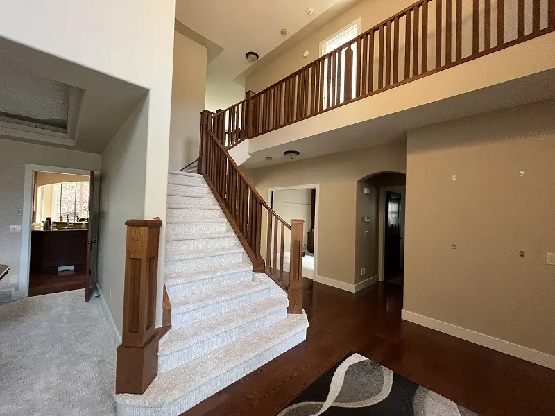 Expert interior painting around staircase and upper hallway in a Calgary residence with elegant neutral finishes.