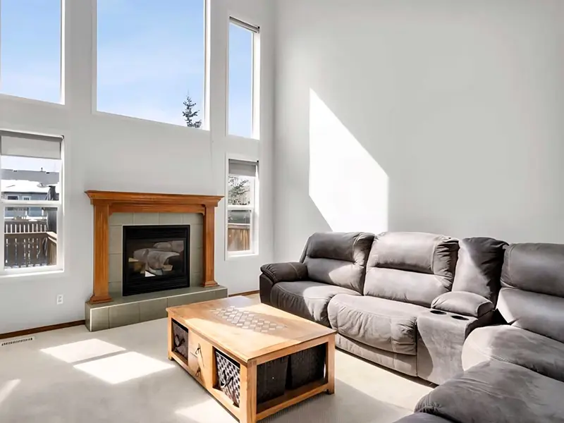 Fresh interior paint enhances a spacious Calgary living room with soaring ceilings, fireplace, and large windows.